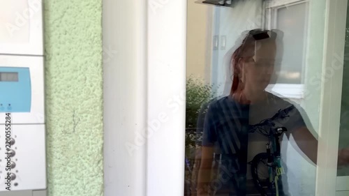 Person using electric lock key fob to enter,access a building door via reader of entry system mounted on a house wall.Close up view
