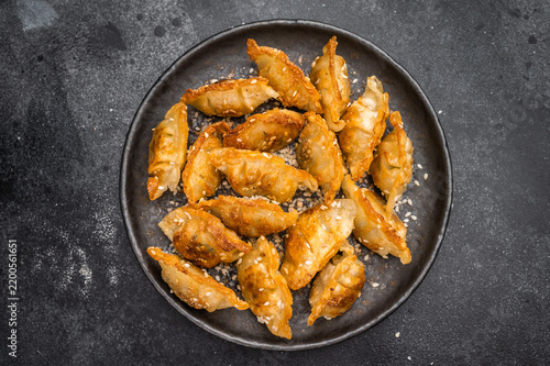 Obraz na plátně Crunchy gyoza wonton dumplings on dark stone background savory Asian dish with g