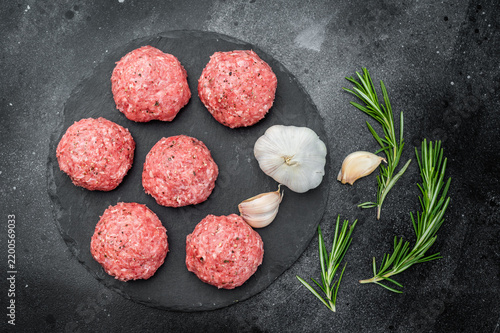 Konstfotografi Fresh raw meatballs or Polpette with rosemary and pepper on round black slate board over dark background ideal for cooking and protein-rich themes