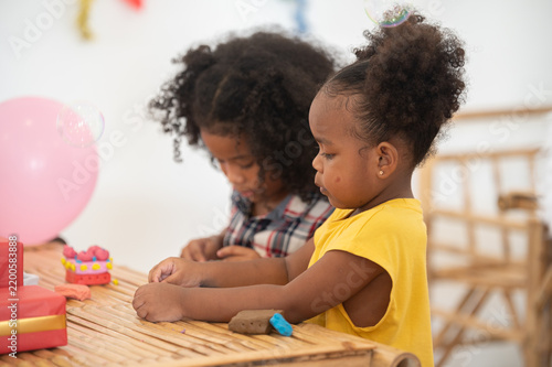 фотографія Two young girls engaged in a creative activity at a festive event, surrounded by colorful decorations and playful elements, promoting friendship and joy