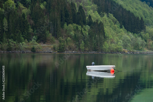 Small boat on calm lake with reflection Norway
