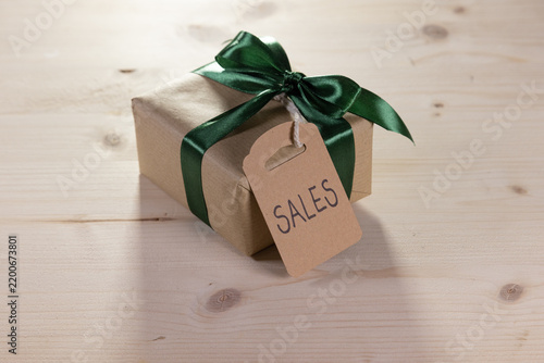 gift with a green bow and a brown label bearing the English word ‘sales’