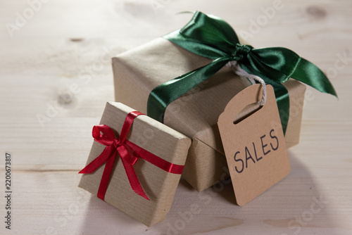 two presents tied with a green and red ribbon, each with a brown label bearing the English word ‘sales’