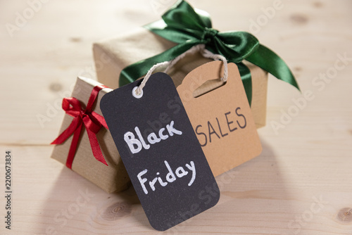 two presents tied with a green and red ribbon, each with a brown label bearing the English word sales and black friday