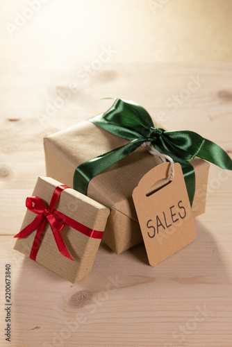 two presents tied with a green and red ribbon, each with a brown label bearing the English word ‘sales’