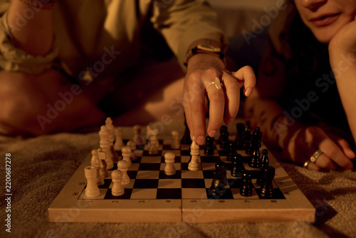 Close up of Caucasian young adult couple playing chess at home, making strategic move. Image suitable for relationship advice, leisure lifestyle, board games marketing