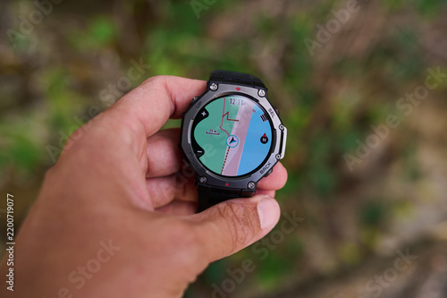 Hand holding smartwatch with GPS navigation map during outdoor hiking