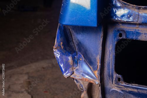 Dented and crushed blue car rear quarter panel fender corner after vehicle collision accident