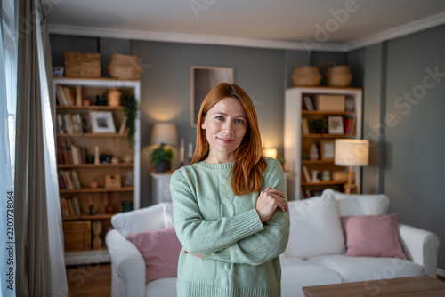 Redhead woman in green sweater smiling at home