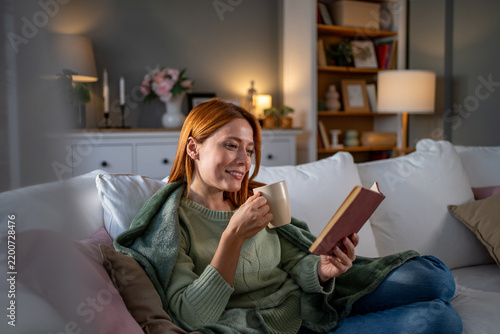 Woman relaxing at home reading book drinking coffee