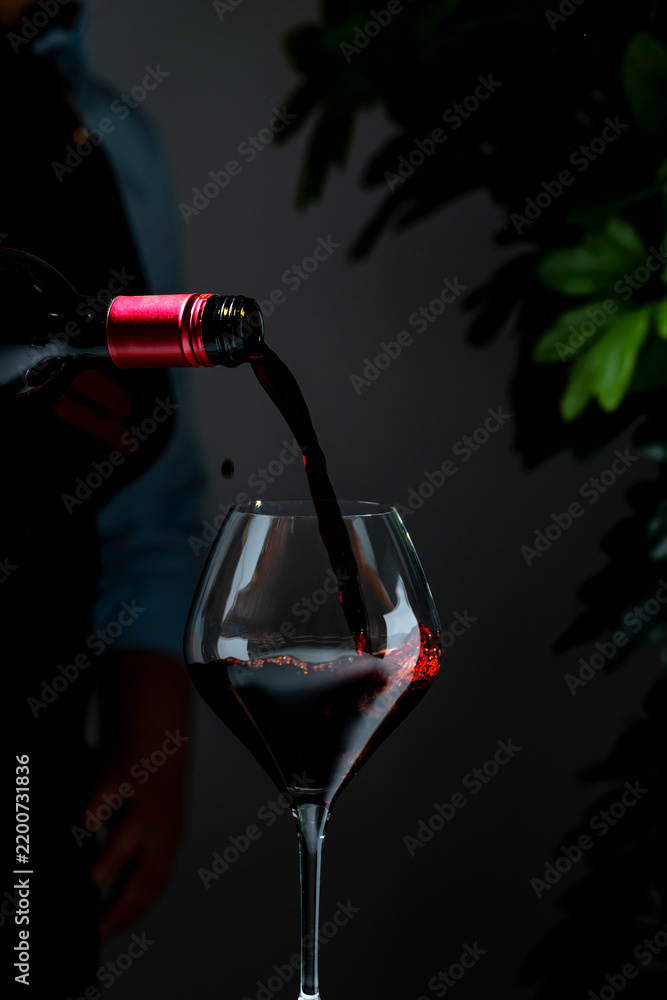Obraz premium Dry Bordeaux red wine in elegant glass — premium hospitality service. Sommelier in dark apron with bottle serving drink at tasting event. Luxury restaurant catering, exclusive celebration.