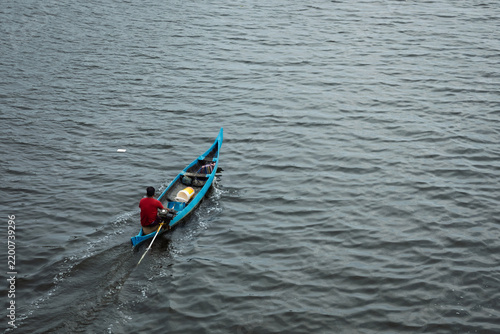 Fotografía Kochi, India a person steering a small, bright blue narrow boat or canoe equippe