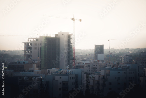 Silhouettes of tower cranes against sun. Limassol, Cyprus