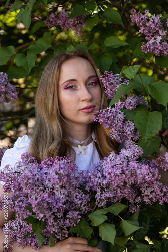 Elegant spring portrait with woman and blooming purple lilac blossoms