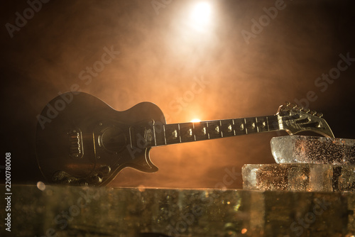 Music Concept: Guitar Miniature on a Dark Background with Vivid Light, Smoke, and Fire Effects. Golden electro guitar under a Dramatic Spotlight.