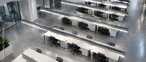 Row of suspended linear ceiling lights above evenly spaced empty desks in a large modern open plan office