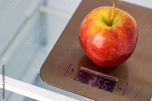 Apple weighing on kitchen scales in empty refrigerator