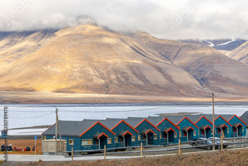 Summer residential view of Longyearbyen with blue wooden houses, calm fjord water and dramatic treeless mountain slopes, Longyearbyen, Spitsbergen, Svalbard, Norway