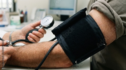 A close up view of a doctor taking a patient blood pressure reading with a manual sphygmomanometer b
