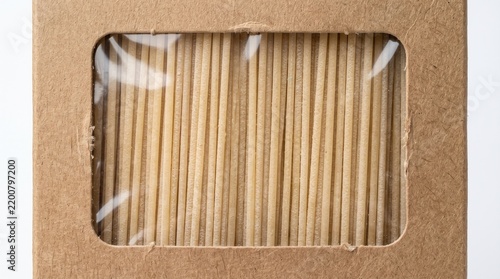 Uncooked spaghetti pasta packaged inside a brown cardboard box with a transparent plastic viewing window against bright studio background.