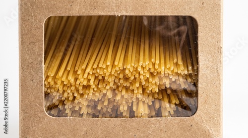 Uncooked spaghetti pasta packaged inside a brown cardboard box with a transparent plastic viewing window against bright studio background.