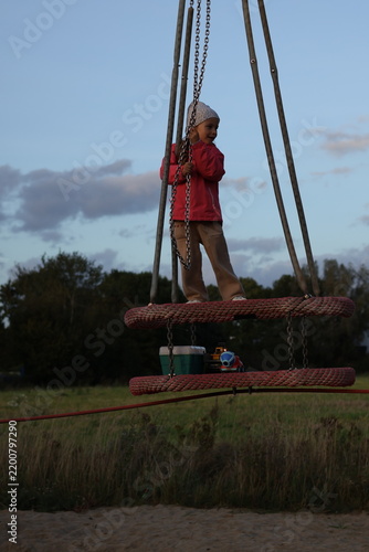 Canvastavla Young girl playing on a playground rope swing structure outdoors at sunset