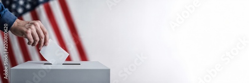 Voter placing a ballot into a ballot box. American flag frames the election setting with copy space. Civic participation and midterm voting concept. Banner with copy space