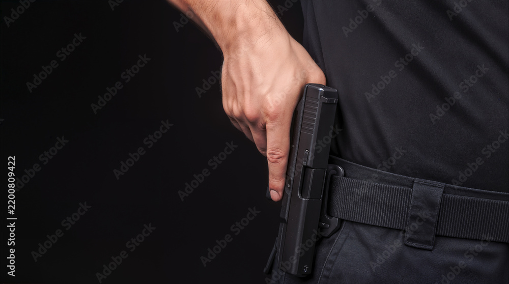 Obraz premium Law enforcement officer reaching for handgun in holster. Tactical gear and firearm readiness for public safety.