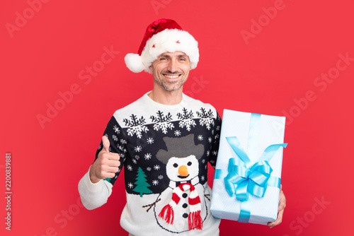 Santa with christmas gift. Portrait of christmas santa man on red studio background.