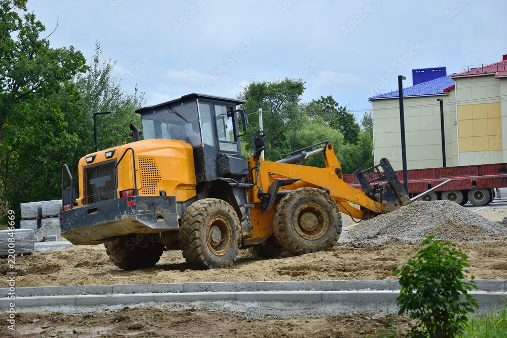 Fototapeta premium Yellow front-end loader is operating on the site.