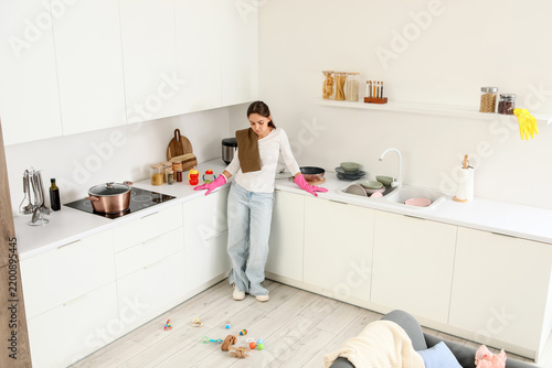 Fotografie Parental burnout and domestic exhaustion, tired mother standing in messy kitchen