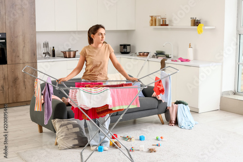 Fotografía Parental burnout and domestic fatigue, tired woman doing laundry chores in messy