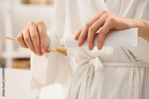 Oral hygiene and sustainable living, woman applying toothpaste on a bamboo toothbrush for daily dental care routine in a bright bathroom environment