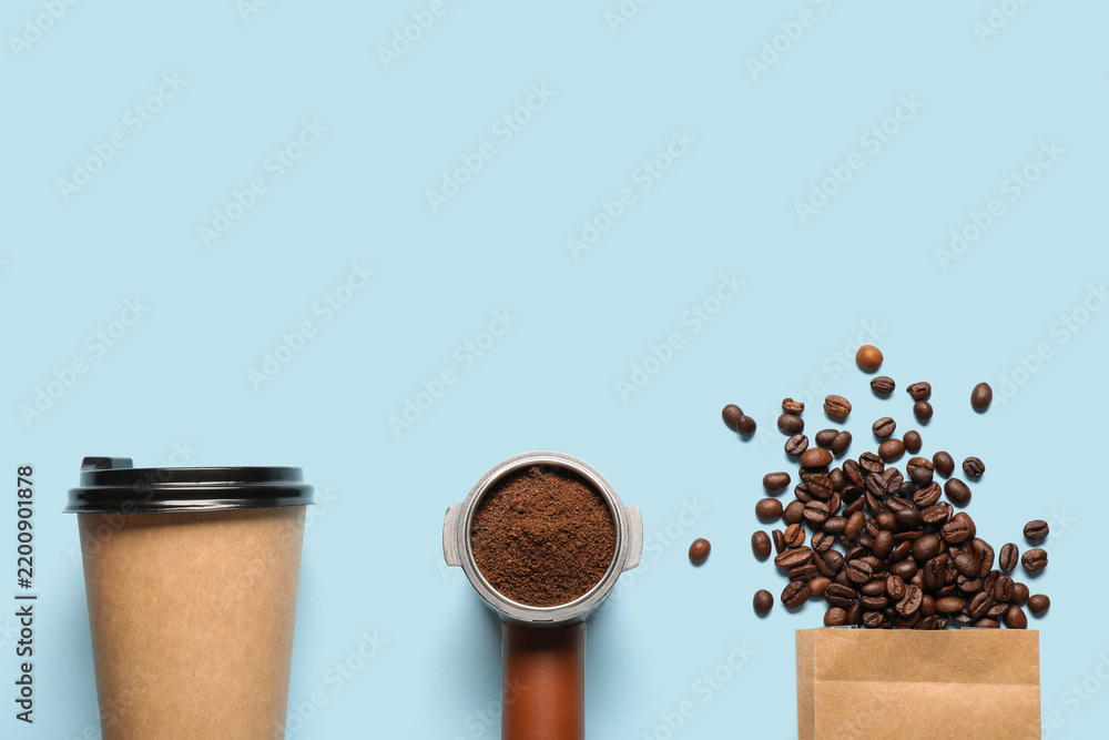 Obraz premium Takeaway cup with coffee bag, beans, portafilter and powder on blue background