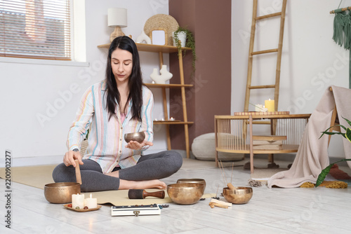 Beautiful woman with Tibetan singing bowls sitting at home