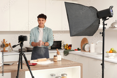 Male blogger preparing dough while recording video in kitchen