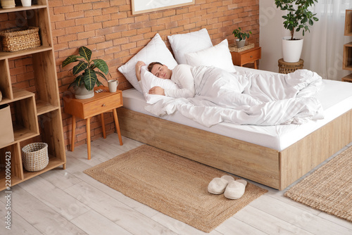 Young man sleeping in cozy bed at home