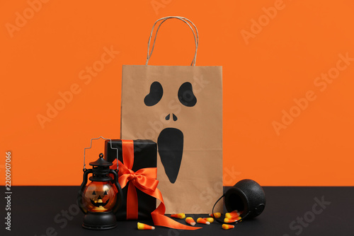 Paper shopping bag, gift box, lantern and candies for Halloween on dark table