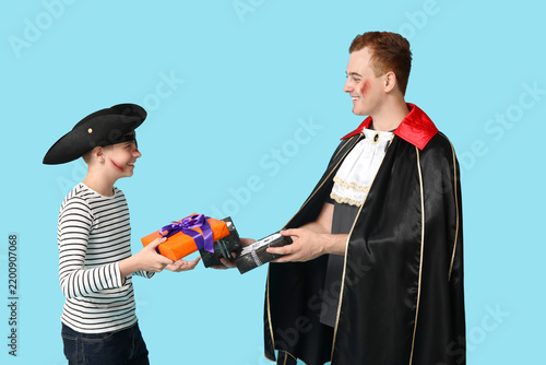 Father and his son dressed for Halloween with gift boxes on blue background