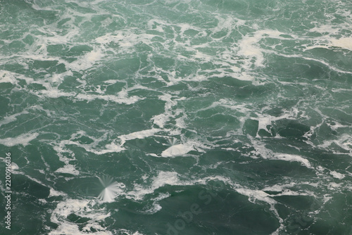 Fotografie Churning teal water veined with white foam from above