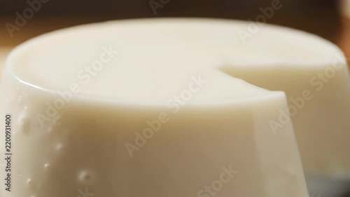Close-up Macro Shot of Creamy White Panna Cotta or Flan Dessert with a Glossy Surface, Highlighting the Smooth Texture and Partially Eaten Slice