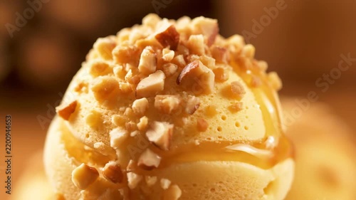 Close-up of gourmet caramel ice cream scoop topped with chopped nuts and rich syrup drizzle, focusing on dessert texture and indulgence and sweet flavor.