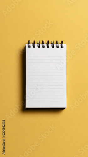 Blank Notebook: A simple blank notebook with lined pages sits open on a vibrant yellow background, ready for new ideas and notes to be jotted down.