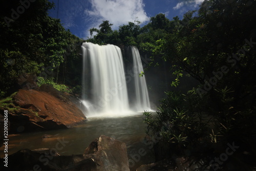 Beautiful Saphan Hin Waterfall hidden in the lush tropical rainforest of Trat Province, Thailand. Long exposure shot of silky water flowing down the rocky cliff.