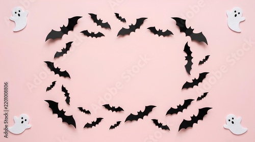 Circle frame of black bat silhouettes and tiny white ghosts on pink background.