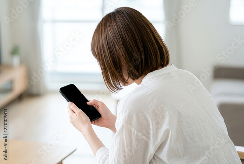 Obraz na płótnie 猫背でスマートフォンを見る日本人女性の後ろ姿と前傾した首｜ストレートネック・姿勢の悩みのイメージ