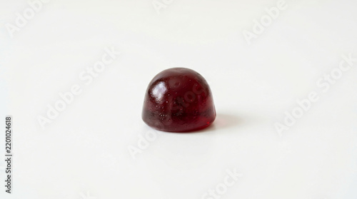 Gummy candy dome in dark red color stands alone in the center of a wide transparent space.