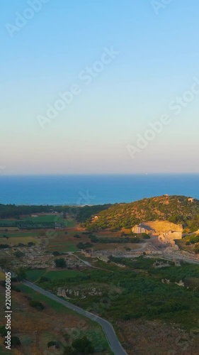 Vertical video. Gelemis, Turkey. Patara Ancient City, aerial view over stone ruins and amphitheatre set against Mediterranean coast and clear summer morning sky. Aerial View. Rich colors