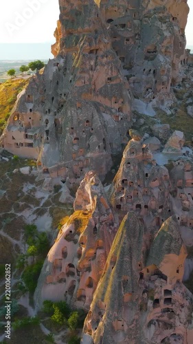Vertical video. Uchisar, Nevsehir, Turkey. Uchisar Castle, the tallest fairy chimney in Cappadocia, honeycombed with ancient cave dwellings and tunnels, aerial panoramic view at golden hour. Aerial V