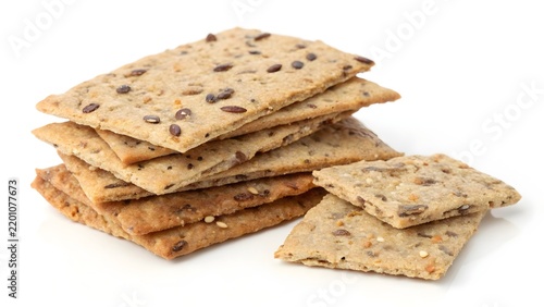 Crispy multigrain crackers packed with nutritious seeds are stacked neatly on a bright white studio background.